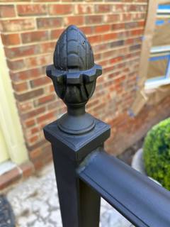 Acorn-shaped finial atop a square black railing post