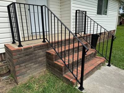Angled view of black railings around brick entrance steps and a landing