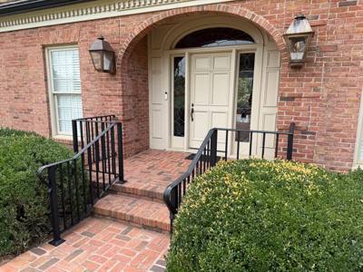 Angled view of black railings framing a brick entry path and stoop