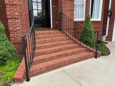 Angled view of curved handrail returns beside wide brick steps