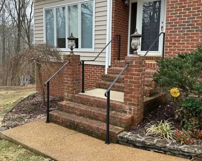 Angled view of plain black handrails on brick entrance steps