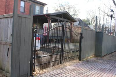 Arched black driveway gate between solid fence panels