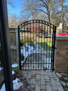 Arched decorative pedestrian gate beside a brick pillar