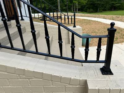 Ball-topped black railing with decorative balusters on a pale brick wall