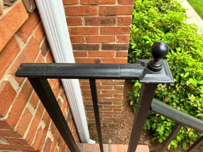 Ball-topped railing post and straight handrail beside a brick wall