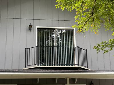 Black balcony railings above a covered porch on a light-sided house