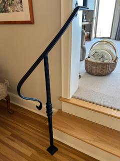 Black curled handrail beside wooden steps leading into a sitting room