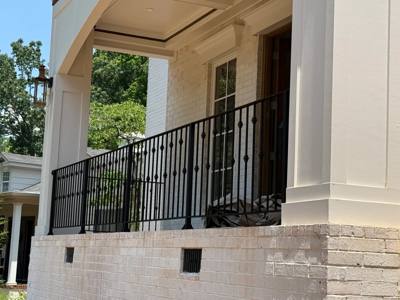 Black decorative railing across a high porch between pale columns