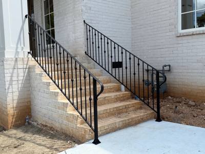 Black decorative railings beside pale masonry steps along a white brick wall