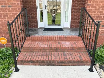 Black decorative railings framing brick entrance steps and glass doors