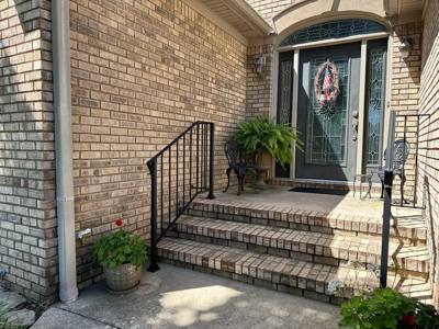 Black decorative railings framing brick steps at an arched entrance