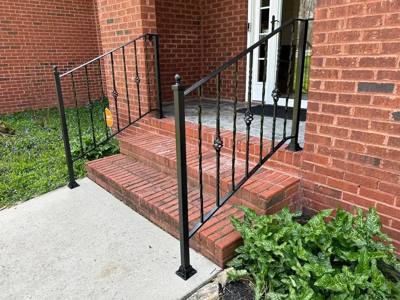 Black decorative stair railings flanking a brick entrance landing