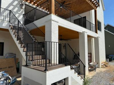 Black exterior staircase connecting two levels of an open covered patio