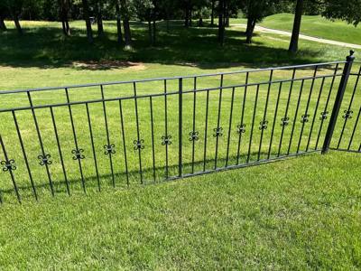 Black fence panel with small decorative motifs across a green lawn