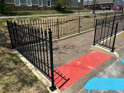 Black fencing bordering an accessible ramp entrance with red tactile paving