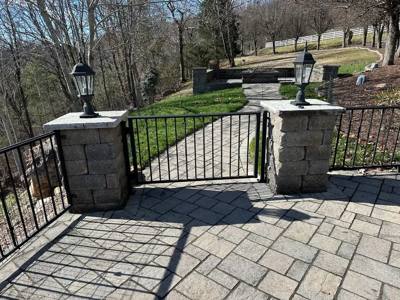Black garden gate between stone pillars topped with lanterns