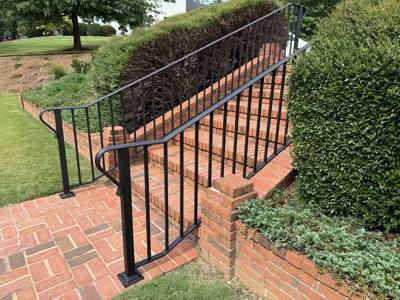 Black handrail following long brick steps along a landscaped slope