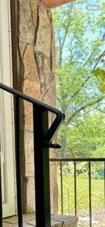 Black handrail wrapping around a stone porch column