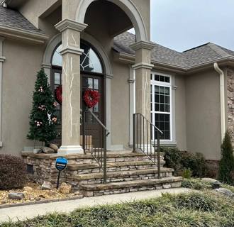 Black handrails at stone entry steps beneath tall porch columns