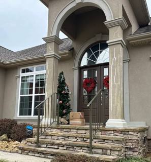 Black handrails at stone front steps beneath a tall arched portico