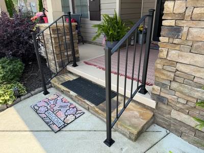 Black handrails beside stone entry steps and a stone-faced column