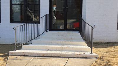 Black handrails beside wide shallow concrete entry steps