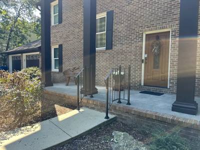 Black handrails bordering a brick landing and short entrance steps