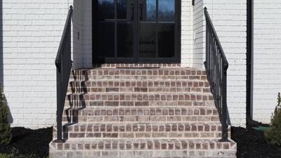 Black handrails flanking broad brick steps at a dark front door
