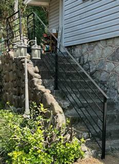 Black handrails following steep stone steps beside a house foundation