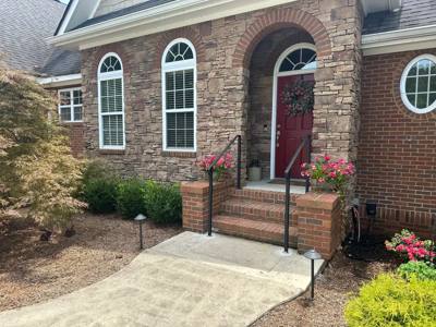 Black handrails framing brick entrance steps beneath an arched doorway
