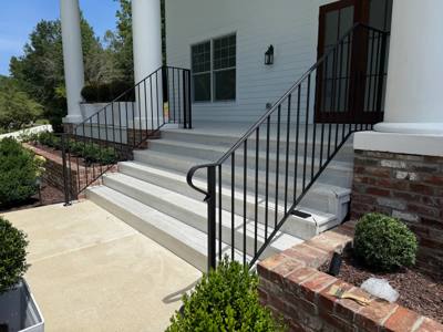 Black handrails framing wide white entry steps beneath a columned porch