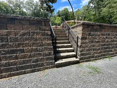 Black handrails on a narrow stairway through tall retaining walls