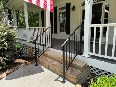 Black handrails on stone steps beside a white porch railing