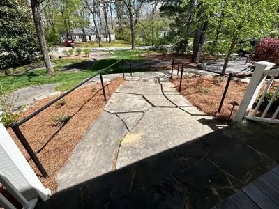Black handrails surrounding a stone walkway viewed from the porch