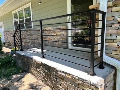 Black horizontal railing around a raised stone porch