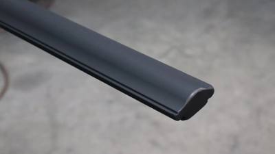 Black molded handrail profile shown against a workshop floor