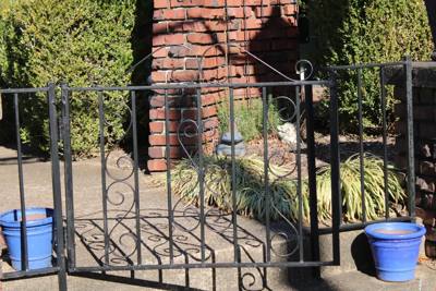Black ornamental railing with repeated scroll panels above brick paving
