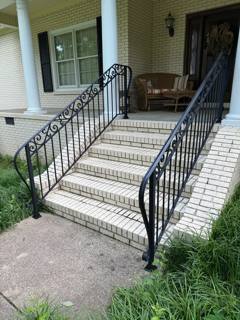 Black ornamental stair railings framing broad white-brick porch steps
