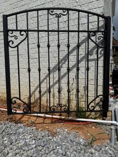 Black pedestrian gate with scroll details and diagonal bracing