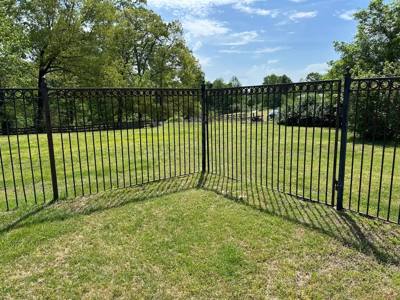 Black picket fence turning at the corner of a green lawn