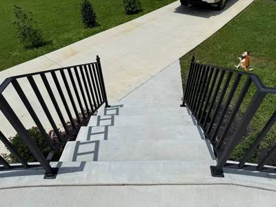 Black picket handrails beside concrete steps descending toward a sidewalk
