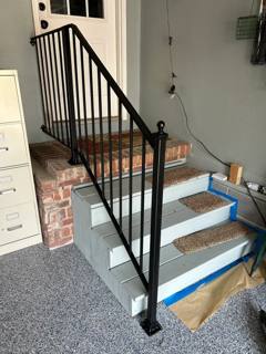 Black picket railing beside interior steps under construction