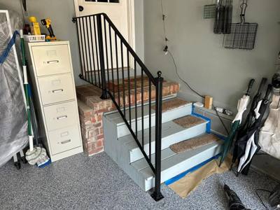 Black picket railing beside short garage steps with unfinished tread edges