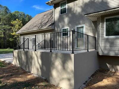 Black picket railing enclosing a raised terrace beside a gray house