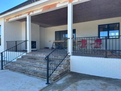 Black picket railings across a broad covered porch and central steps