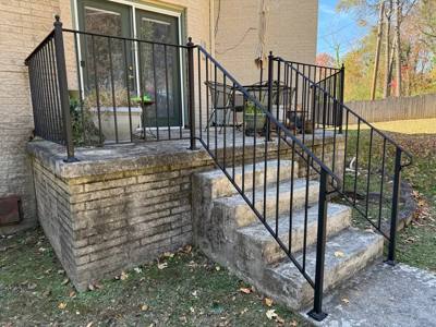 Black picket railings around a raised stone patio and entry steps