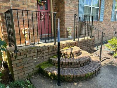 Black picket railings around curved brick entrance steps
