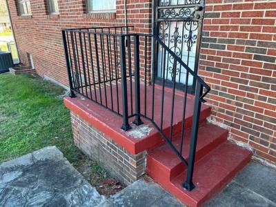 Black picket railings around red-painted steps beside a brick wall