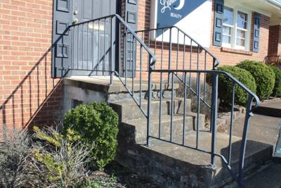 Black picket railings beside a concrete stairway at a brick building