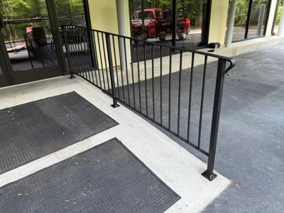Black picket railings beside a glazed entrance and dark floor mats